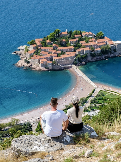 Couple overlooking Sveti Stefan island and beach in Montenegro.