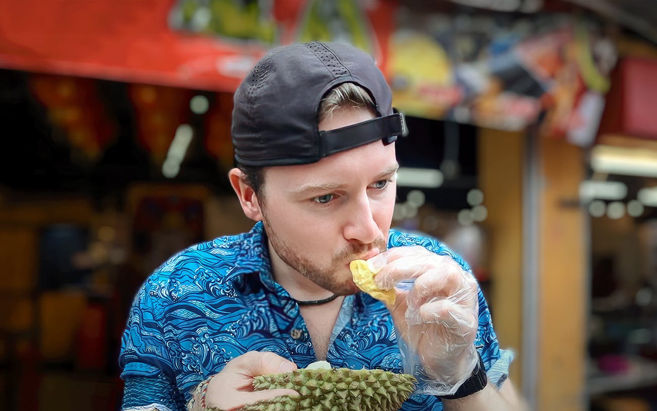 Man tasting durian during Penang street food tour.