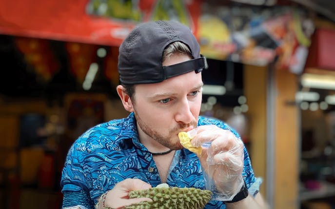 Man tasting durian during Penang street food tour.