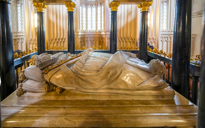 Tomb inside Westminster Abbey with ornate columns and detailed carvings.