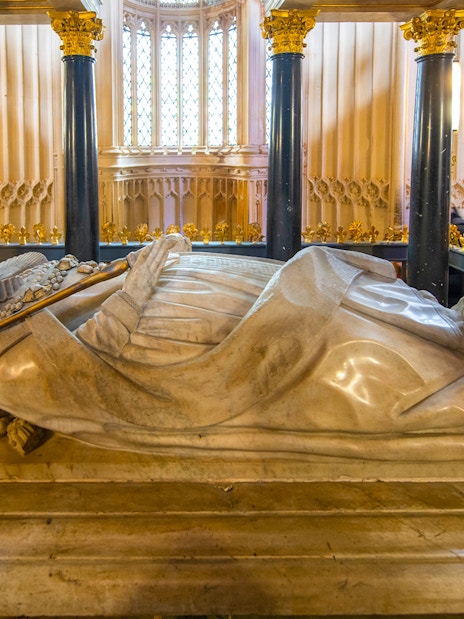 Tomb inside Westminster Abbey with ornate columns and detailed carvings.