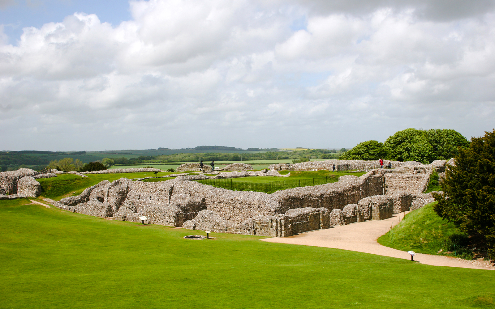 Old Sarum ruins with green landscape and cloudy sky in Salisbury, England.