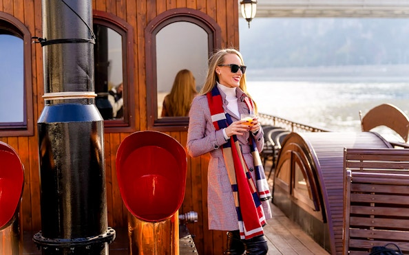 Woman enjoying a drink on a historic cruise in Budapest.