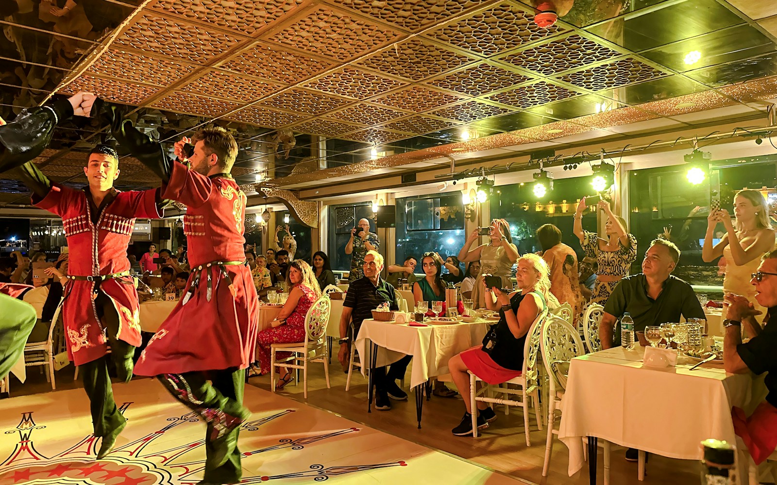 Bosphorus dinner cruise with Turkish show, private table, Istanbul skyline in background.