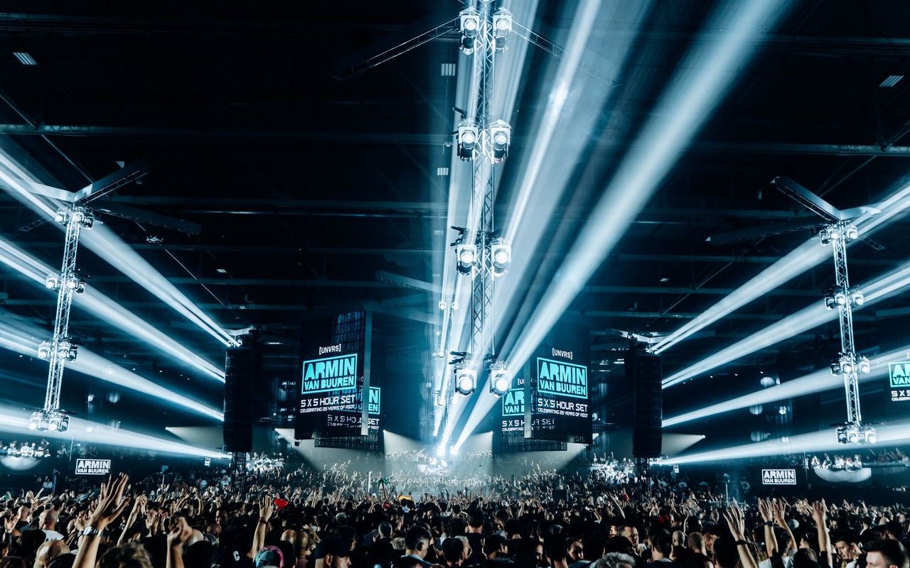 Armin Van Buuren performing live with vibrant lights and crowd in Ibiza.