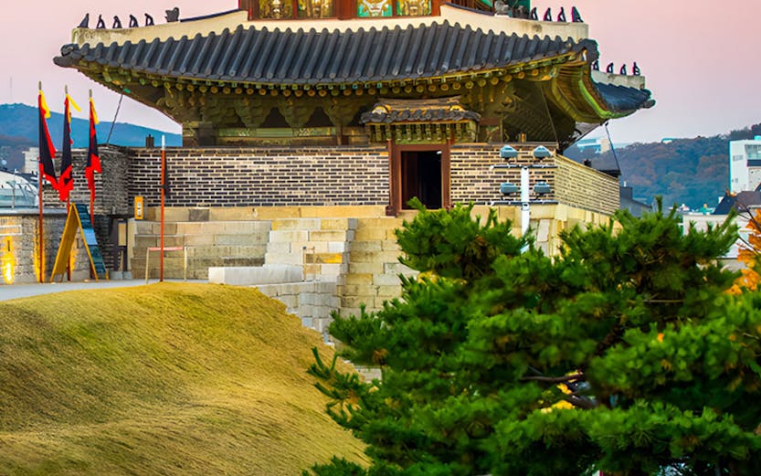 Traditional Korean pavilion at Korean Folk Village with surrounding greenery.