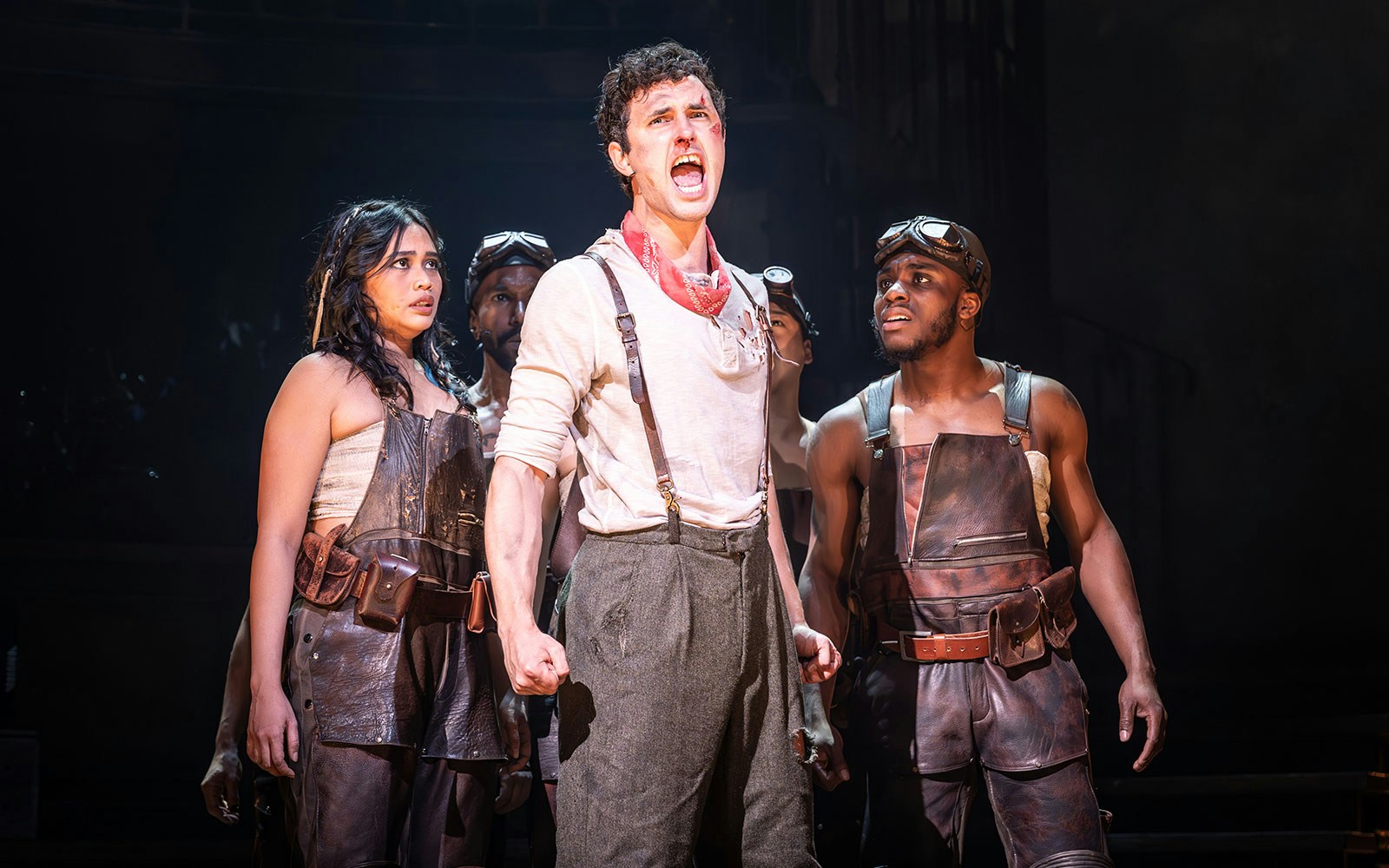Performers in leather attire on stage during a dramatic scene in a ghost stories play.