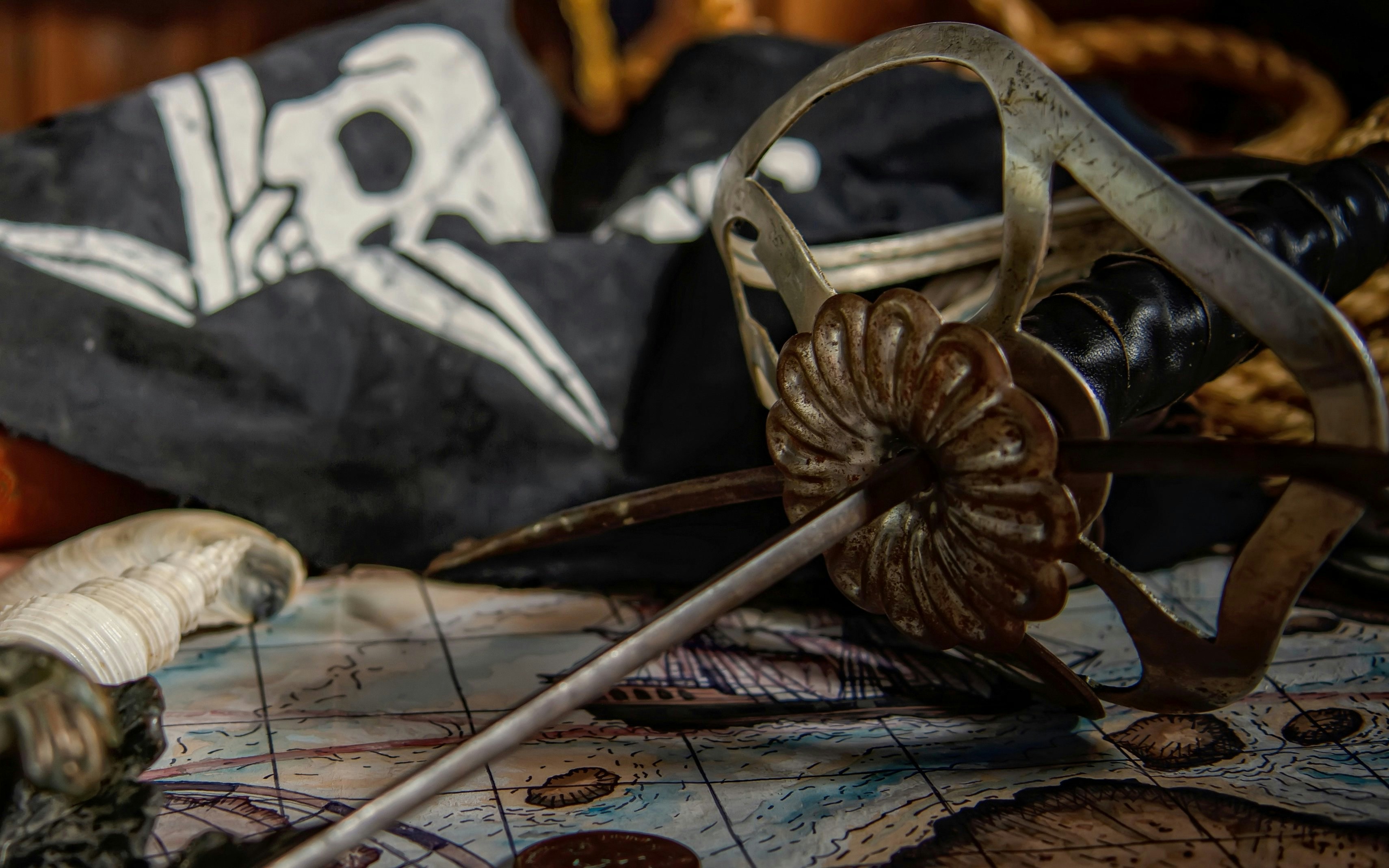 Pirate sword and map with skull flag in the background.