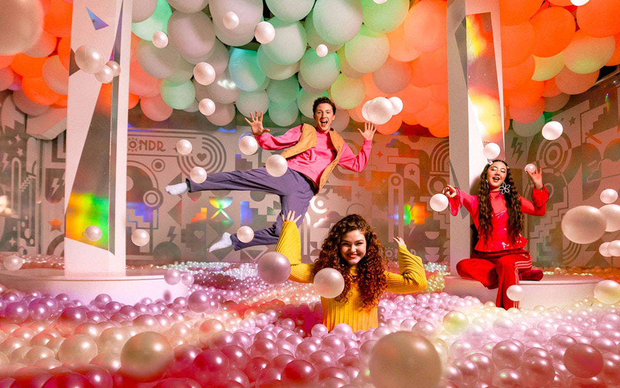 Visitors enjoying colorful ball pit at WONDR Experience.