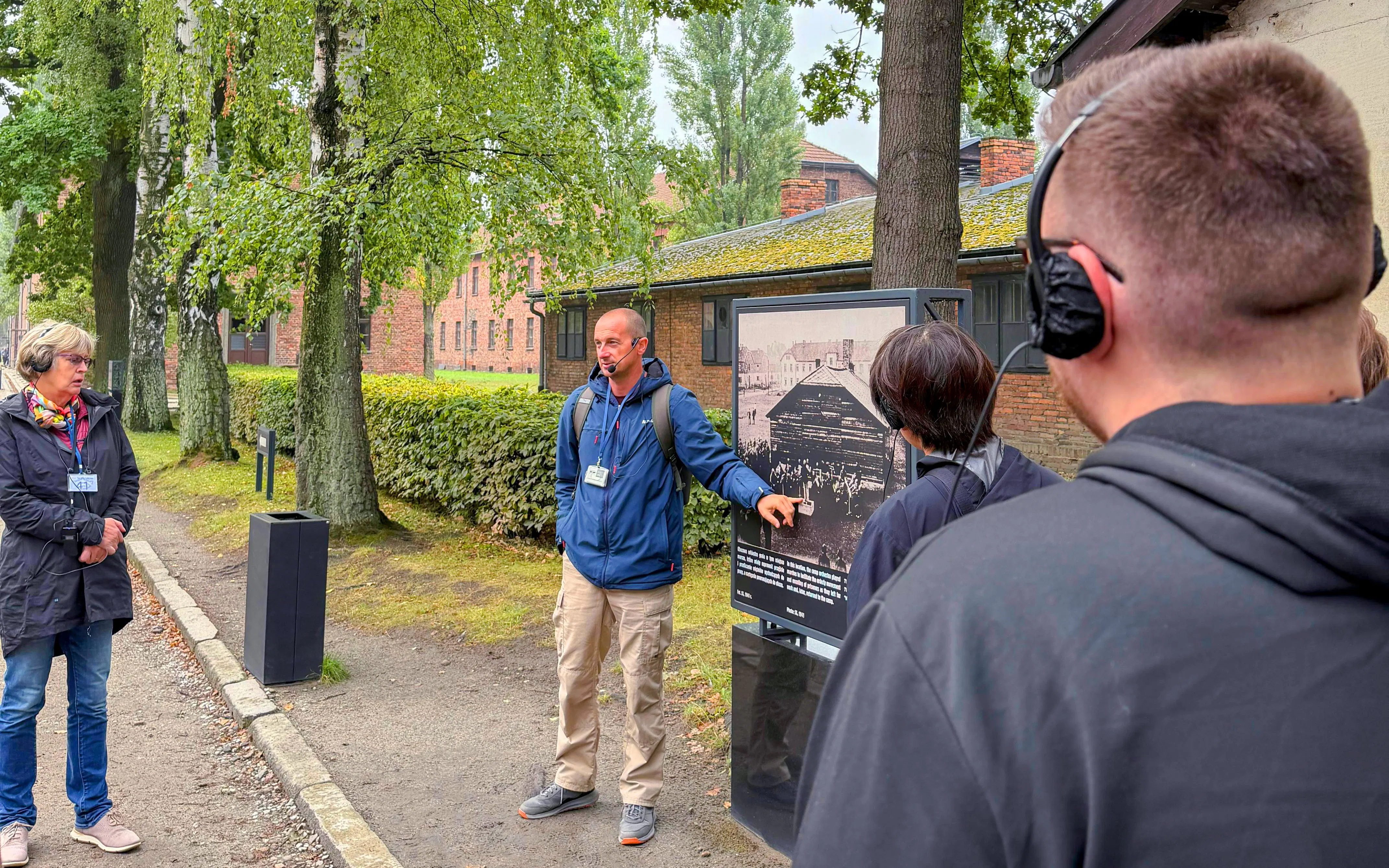 Guide explaining historical photo during Auschwitz-Birkenau tour.