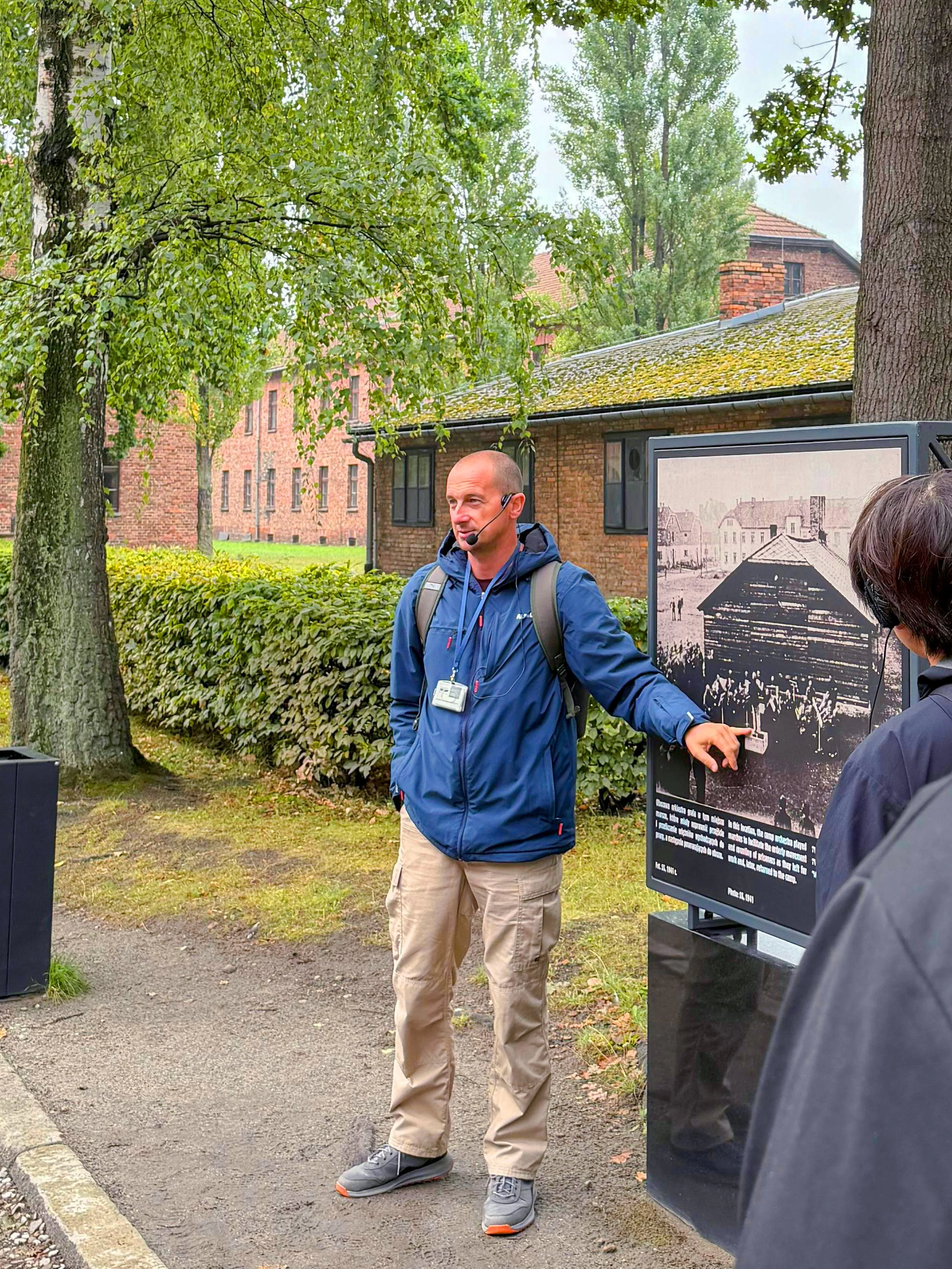 Guide explaining historical photo during Auschwitz-Birkenau tour.