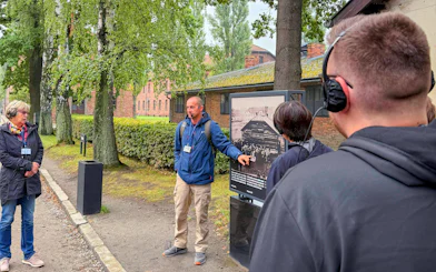 Guide explaining historical photo during Auschwitz-Birkenau tour.
