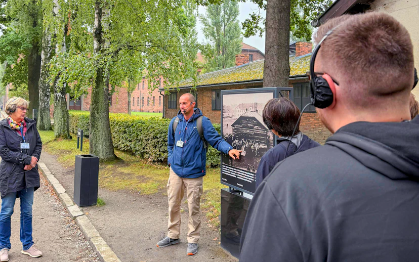 Guide explaining historical photo during Auschwitz-Birkenau tour.