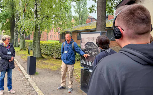 Guide explaining historical photo during Auschwitz-Birkenau tour.