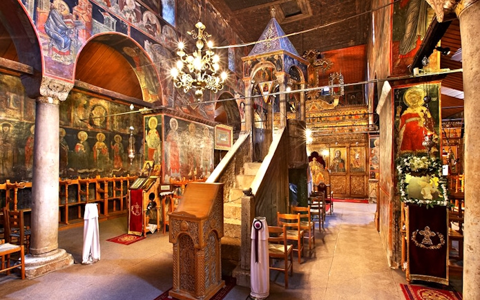 Interior of Varlaam Monastery with frescoes and ornate wooden iconostasis.