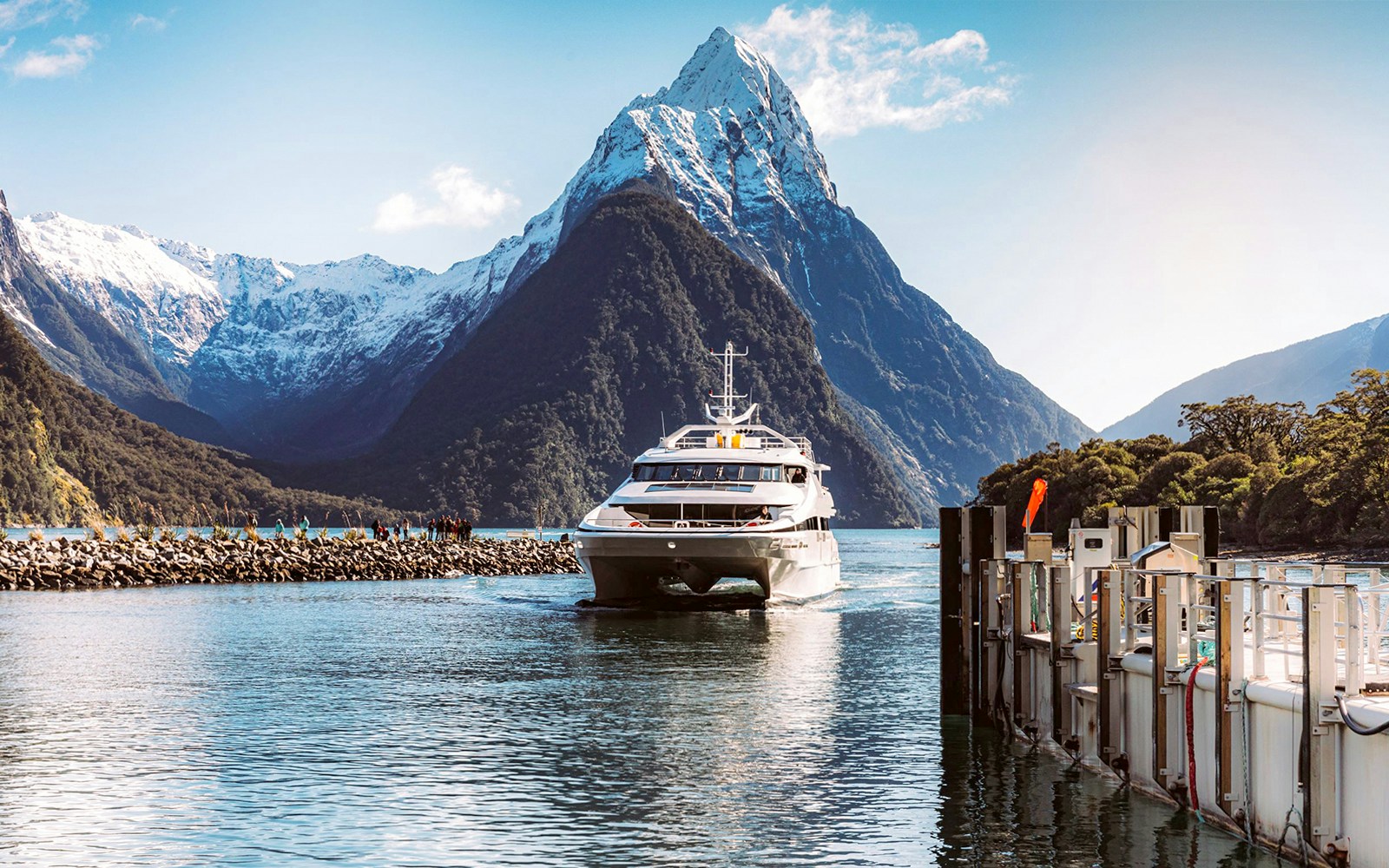 Milford Sound cruise boat with scenic fjord views, lush mountains, and waterfalls, New Zealand day trip.