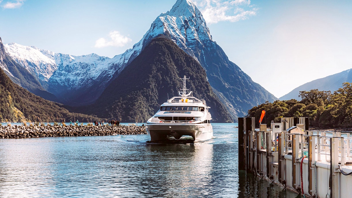Milford Sound cruise boat with scenic fjord views, lush mountains, and waterfalls, New Zealand day trip.