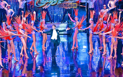 Calypso Cabaret performers in vibrant costumes on stage in Bangkok.