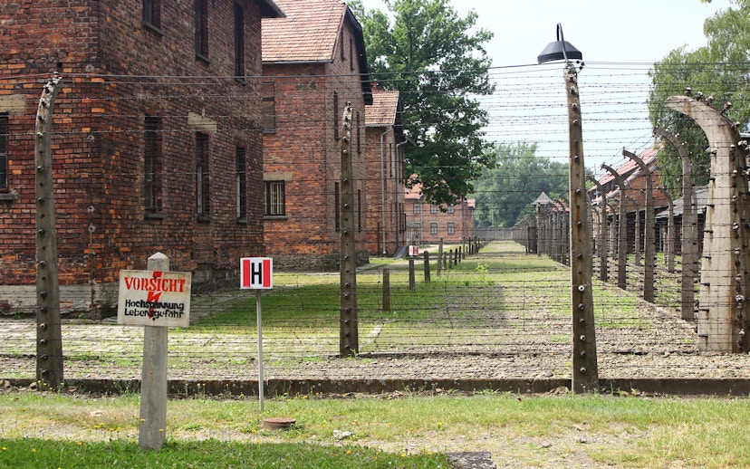 Barbed wire fence and brick buildings at Auschwitz sub-camp, Poland.