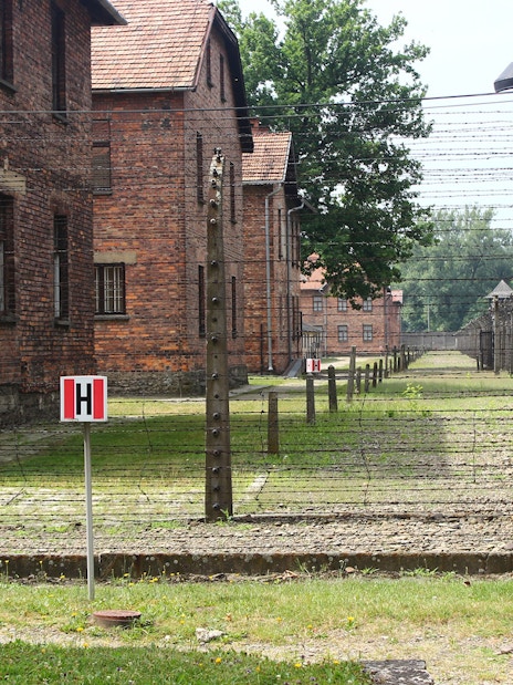 Barbed wire fence and brick buildings at Auschwitz sub-camp, Poland.