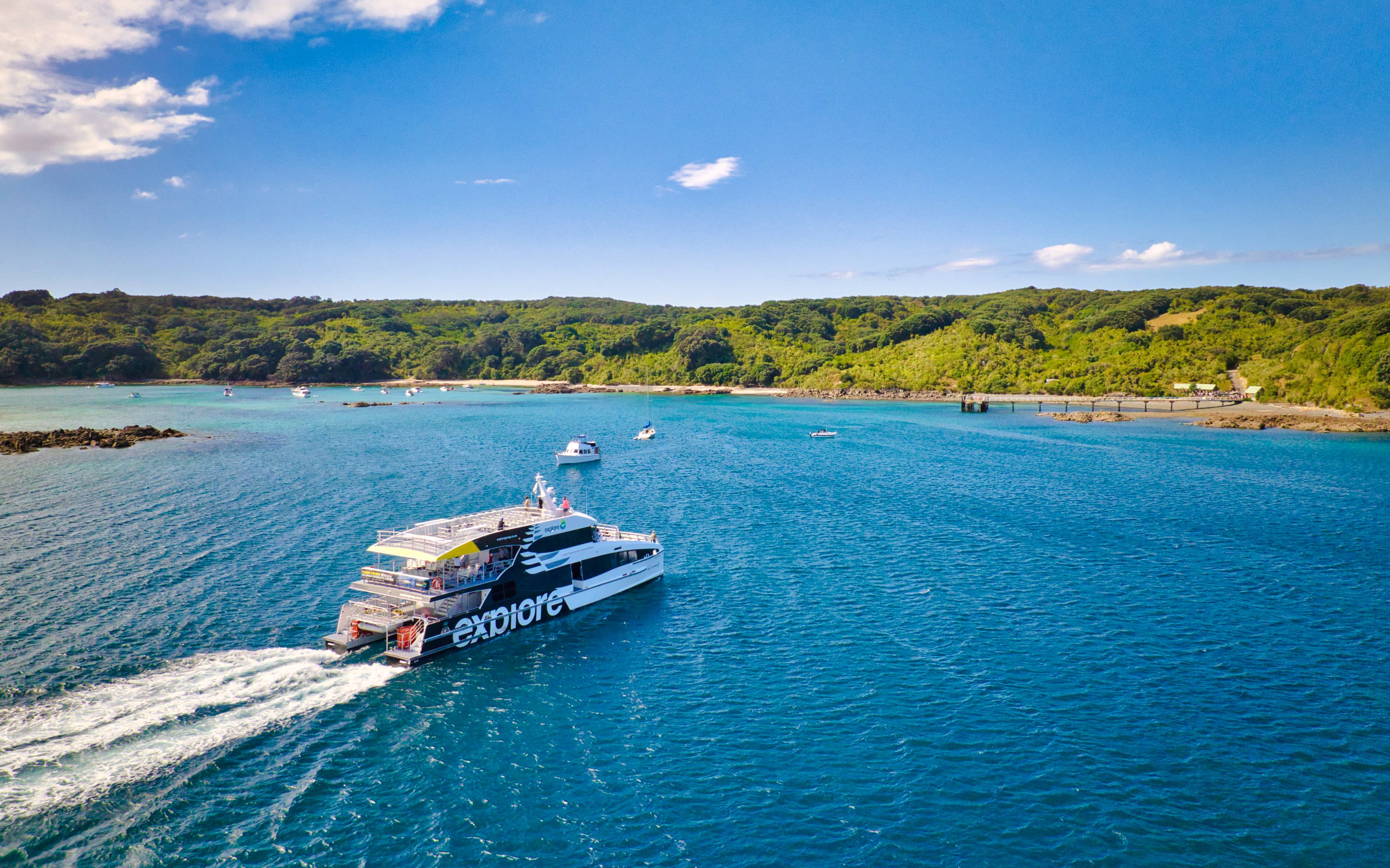 Ferry approaching Tiritiri Matangi Island from Auckland across blue waters.