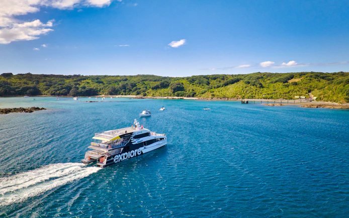 Ferry approaching Tiritiri Matangi Island from Auckland across blue waters.