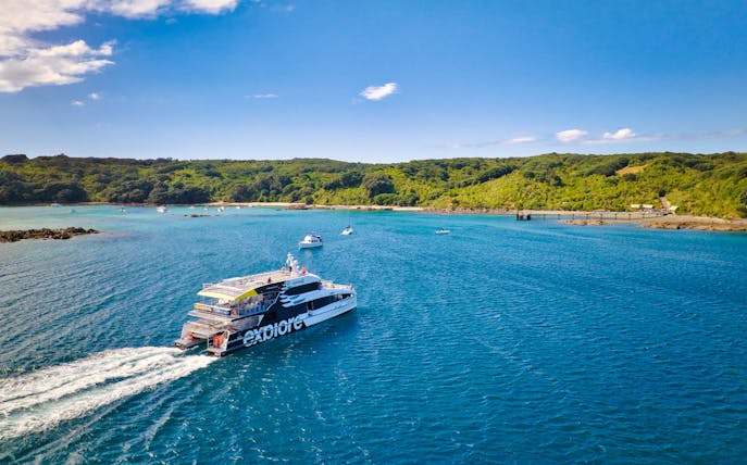 Ferry approaching Tiritiri Matangi Island from Auckland across blue waters.