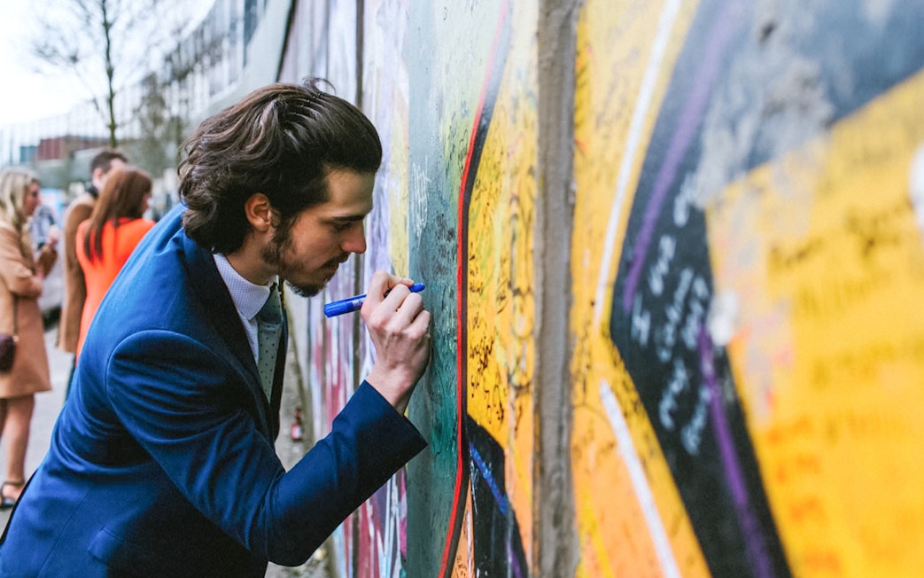 Man writing on Belfast Peace Wall during guided political taxi tour.