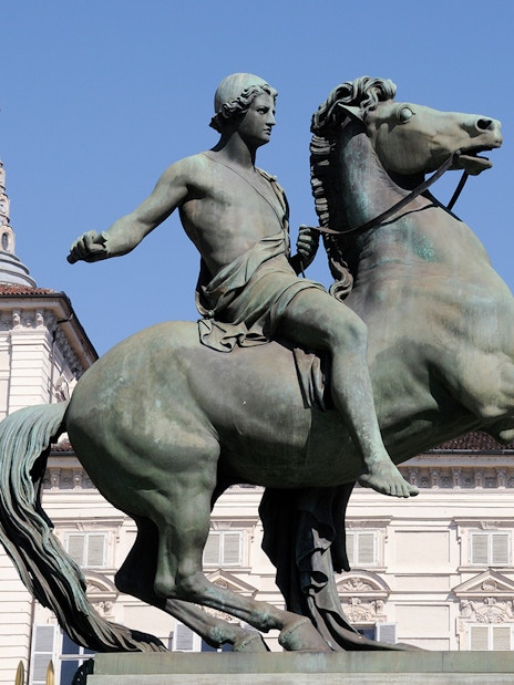 Equestrian statue in front of Royal Palace Museum, Turin, with Italian flag.