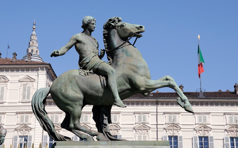 Equestrian statue in front of Royal Palace Museum, Turin, with Italian flag.
