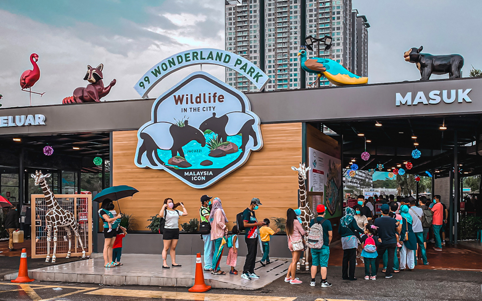 Visitors queue at the entrance of 99 Wonderland Park, Kuala Lumpur, with animal sculptures above.
