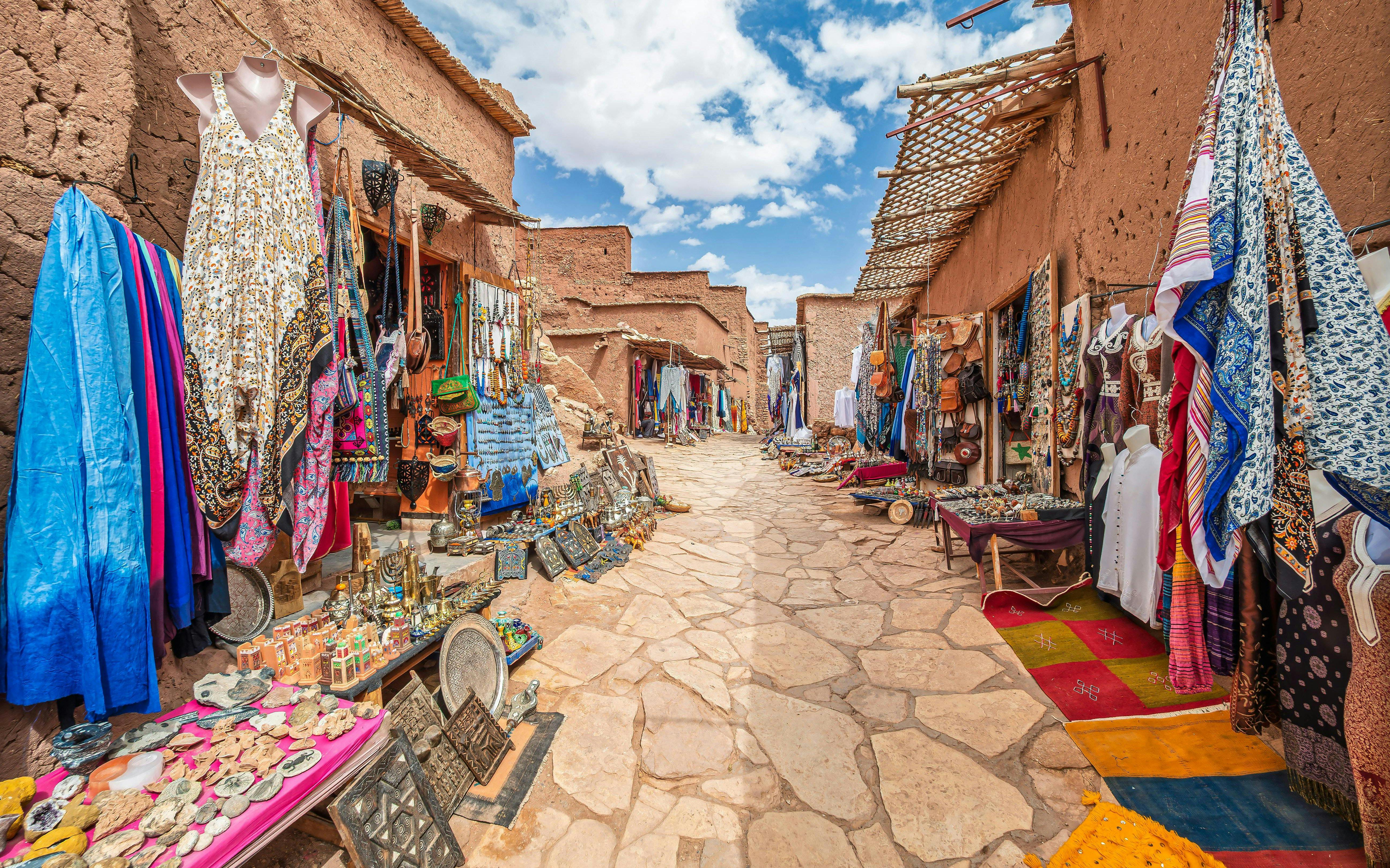 Traditional market stalls with textiles and crafts in Kasbah Ait Ben Haddou, Morocco.