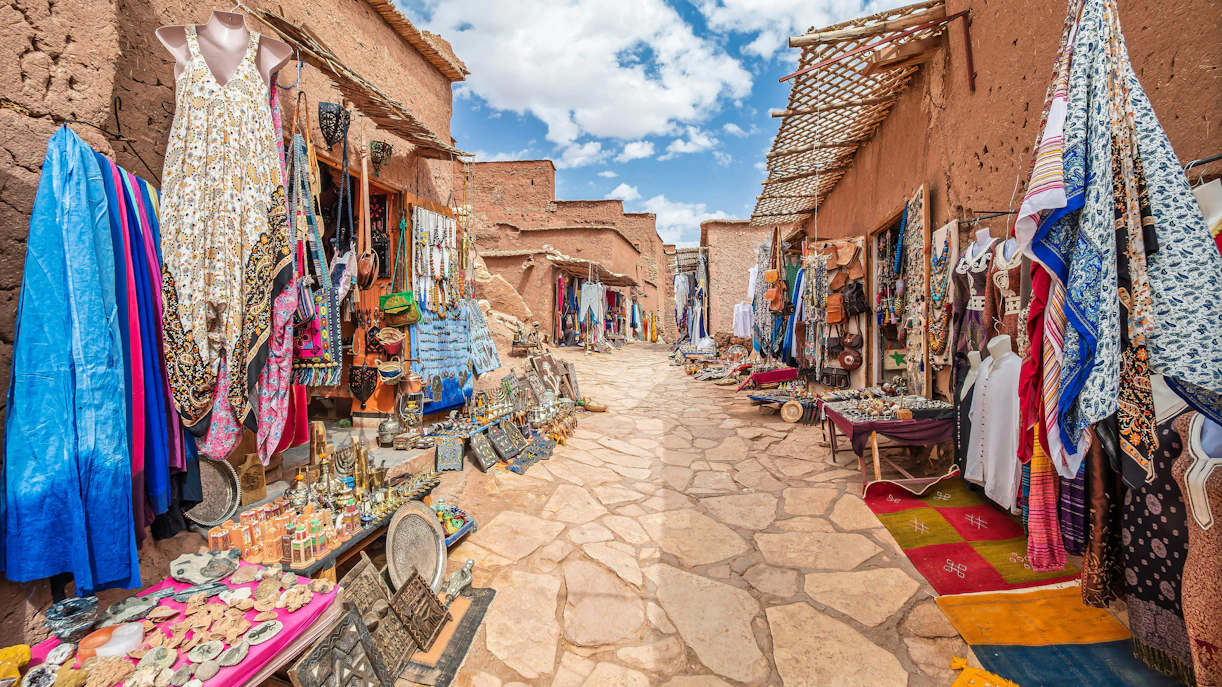 Traditional market stalls with textiles and crafts in Kasbah Ait Ben Haddou, Morocco.