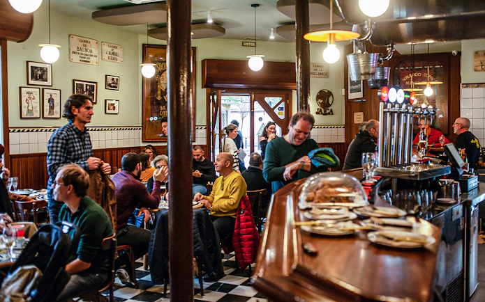 People enjoying a meal in a bustling La Barceloneta restaurant during a guided food tour.
