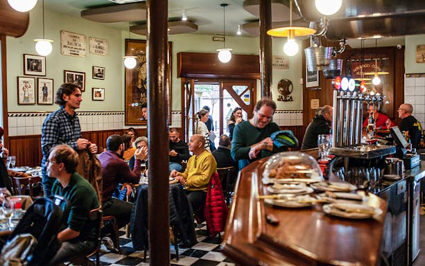 People enjoying a meal in a bustling La Barceloneta restaurant during a guided food tour.