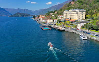 Aerial view of Lake Como with a boat near the shoreline and mountains in Lombardy, Italy.