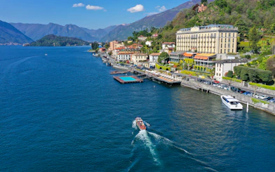 Aerial view of Lake Como with a boat near the shoreline and mountains in Lombardy, Italy.