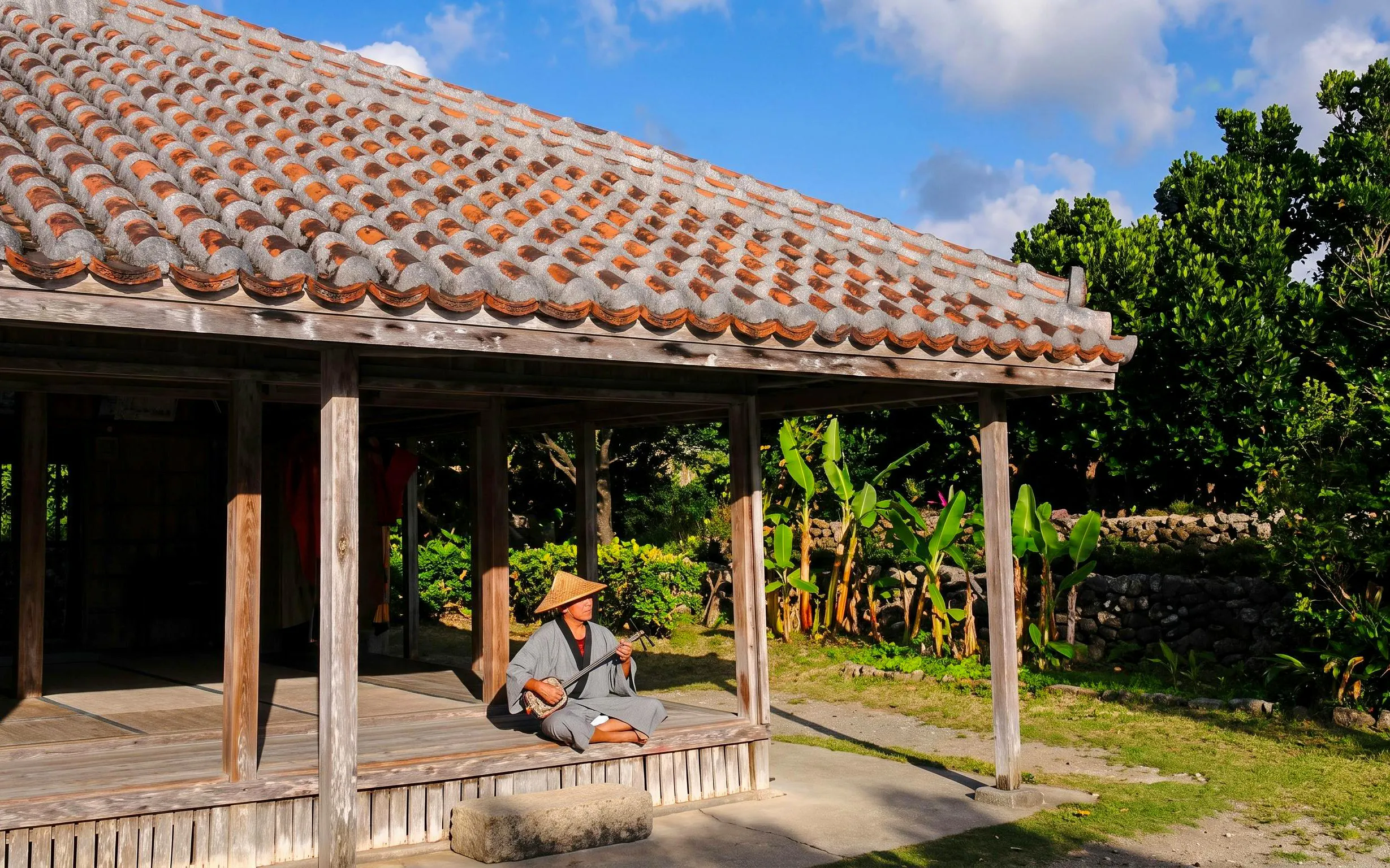 Man playing traditional instrument at Ishigaki Yaima Village, Okinawa, Japan.