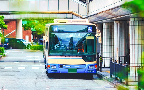 Osaka city bus with passengers boarding on a busy street.