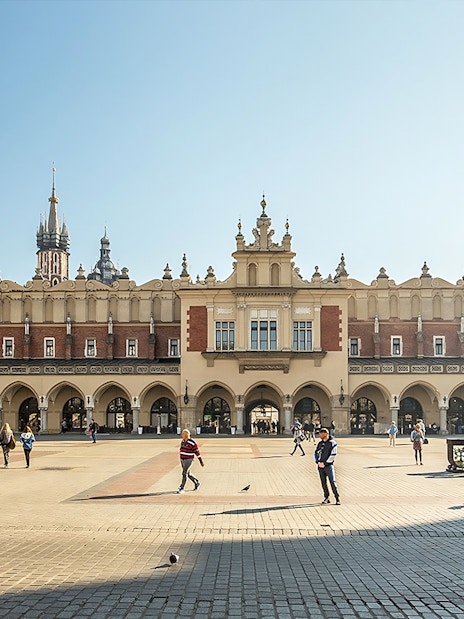 MNK Sukiennice exterior with people walking in Kraków's main square.