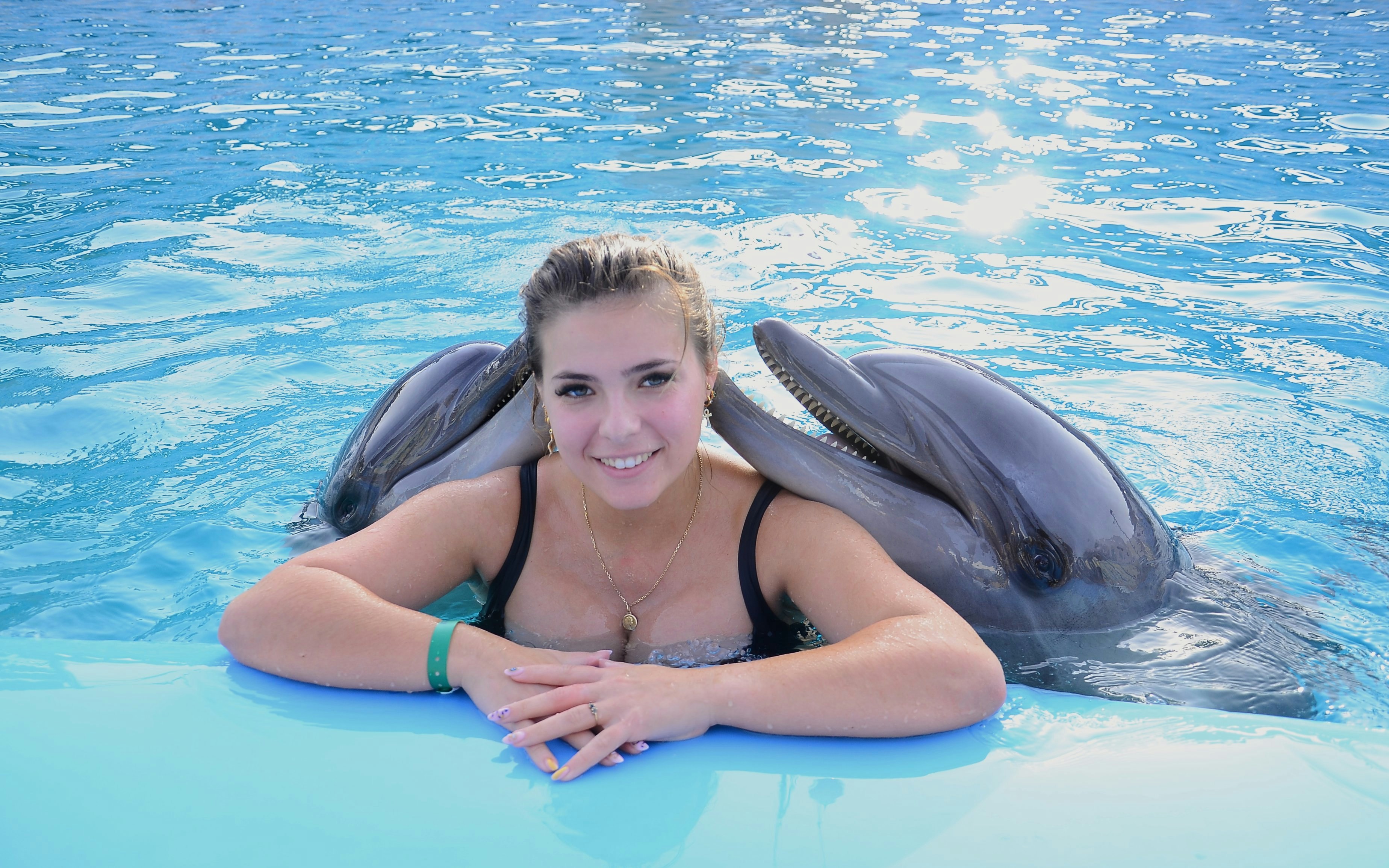 Woman with two dolphins at Hurghada Dolphin Show, Egypt Dolphin World.