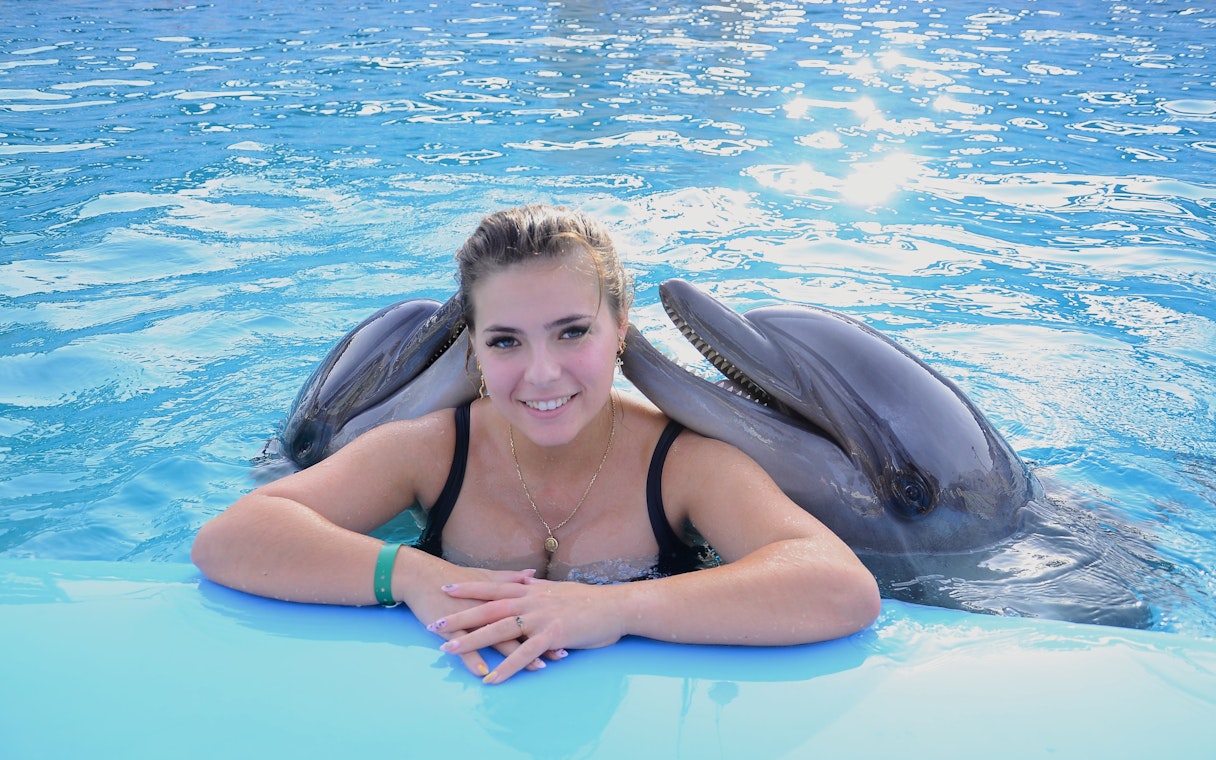 Woman with two dolphins at Hurghada Dolphin Show, Egypt Dolphin World.
