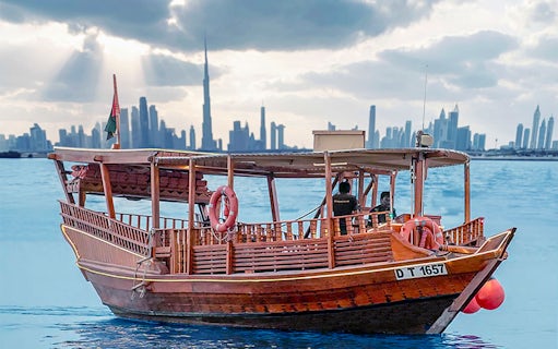 Abra boat on Dubai Creek with Burj Khalifa at sunset in the background.