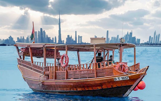 Abra boat on Dubai Creek with Burj Khalifa at sunset in the background.