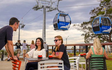 People enjoying coffee on a deck with Arthurs Seat Eagle gondola in the background.