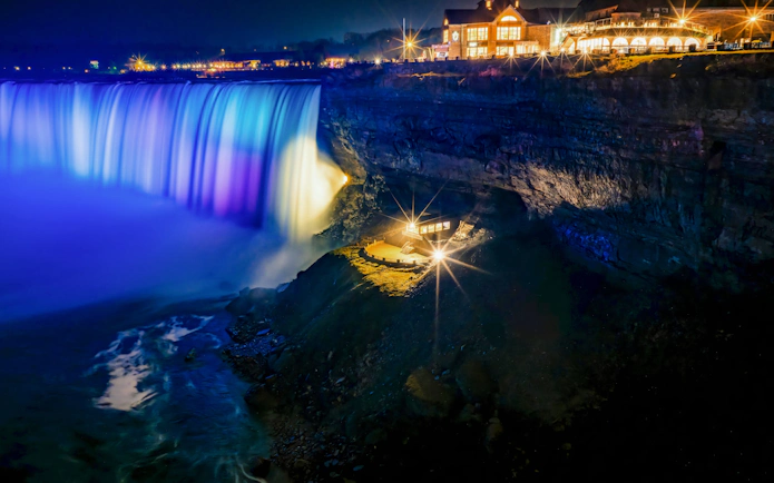 Journey Behind the Falls at night with illuminated waterfall and observation deck.