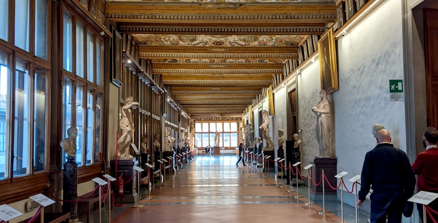 Uffizi Gallery corridor with Renaissance sculptures and ornate ceiling, Florence Wonders Tour.