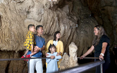 Family exploring Waitomo Caves with a guide, part of the Auckland Hobbiton Movie Set tour.