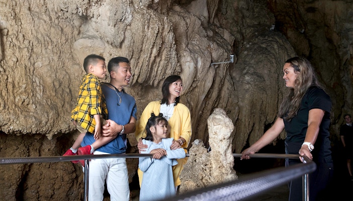 Family exploring Waitomo Caves with a guide, part of the Auckland Hobbiton Movie Set tour.