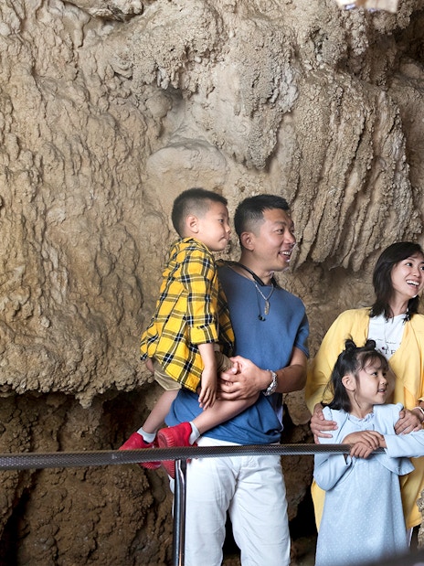 Family exploring Waitomo Caves with a guide, part of the Auckland Hobbiton Movie Set tour.